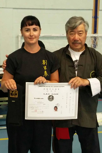 Carly Anderson at the Summer Course, receiving her Black Sash and Certificate from Master Yau